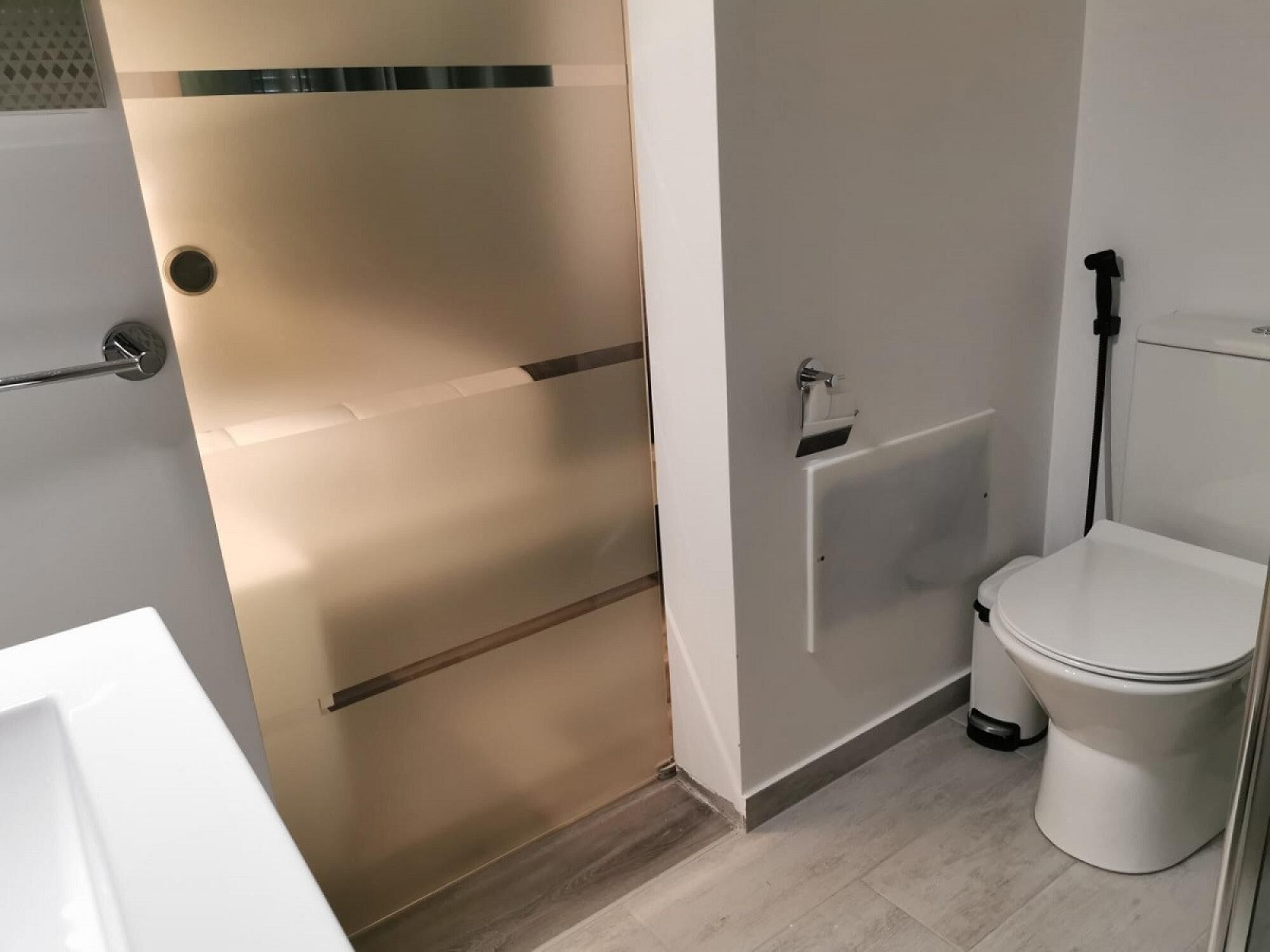 Un baño con inodoro, lavamanos y zona de ducha.