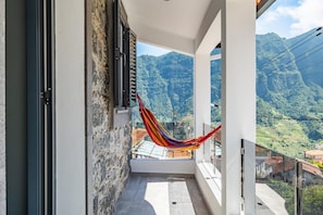 Relax in a hammock on this balcony with a serene mountain view.
