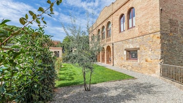 A historic building with a courtyard, stone walls, and a well-maintained lawn.
