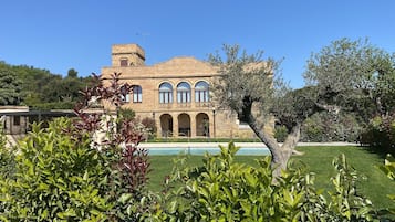 A large, historic building with a courtyard, arched windows, and a swimming pool.