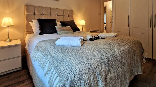 A neatly made bed with a grey blanket, two bedside lamps, and a headboard with a tufted design. - 2 Bed Apartment in Leafy Sandymount, Dublin 4 (Dublin 4)