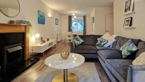 A modern living room with a dark grey sofa, a round marble coffee table, a TV, and a small white side table. - 2 Bed Apartment in Leafy Sandymount, Dublin 4 (Dublin 4)