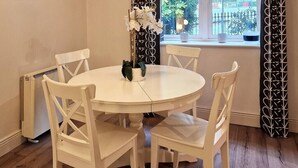 A round white table with four white chairs, a potted plant, and a window with a view of greenery and a fence. - 2 Bed Apartment in Leafy Sandymount, Dublin 4 (Dublin 4)