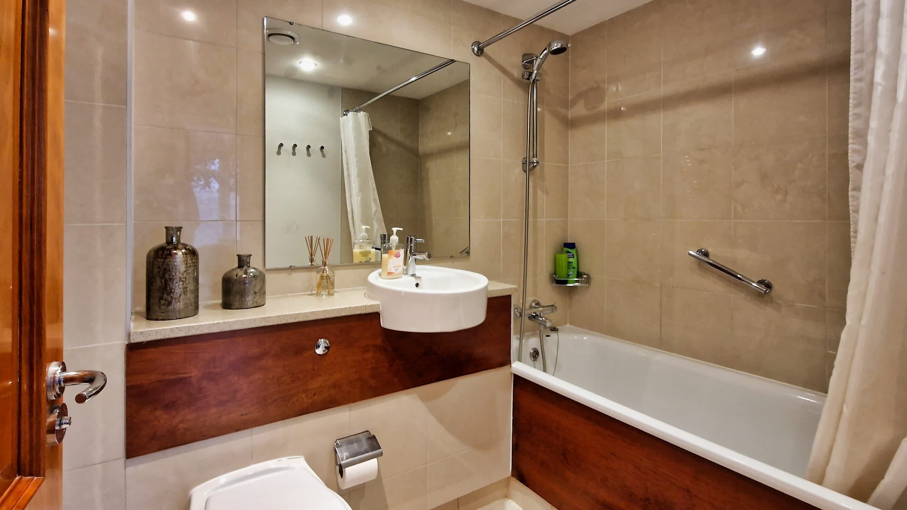 Une salle de bain moderne avec un meuble-lavabo, un évier, un miroir et une douche à l’italienne.