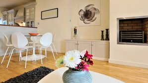 A modern kitchen with white cabinetry, a dining area with white chairs, and a black rug.