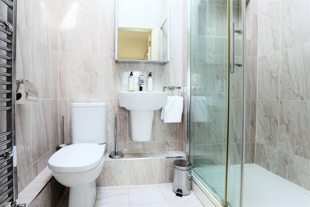 Un baño moderno con inodoro, lavamanos y cabina de ducha de vidrio.