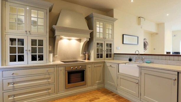 A kitchen with wooden flooring, double sinks, and built-in cabinets.
