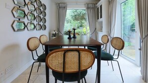 A dining room with a rectangular table, six rattan chairs, and a wall decorated with hexagonal mirrors. - Elegant and contemporary large 3 bedroom home (Dublin)