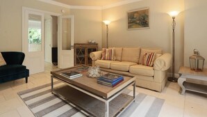 A living room with a beige sofa, a coffee table with books and decorative items, a dark armchair, and a painting on the wall. - Elegant and contemporary large 3 bedroom home (Dublin)