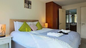 A neatly made bed with pillows, a bedside lamp, and a towel on the bed.