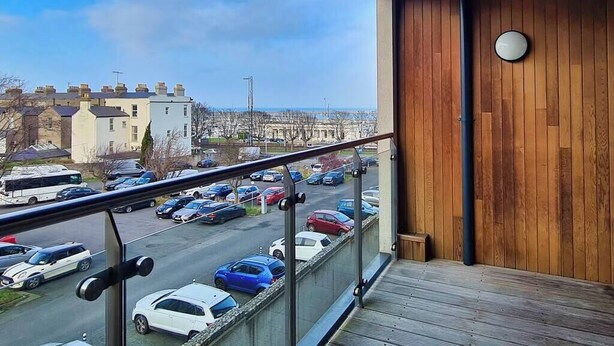 A balcony with a view of a parking lot and buildings.