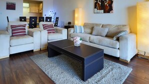 A modern living room with a sofa set, a coffee table, and a painting on the wall.