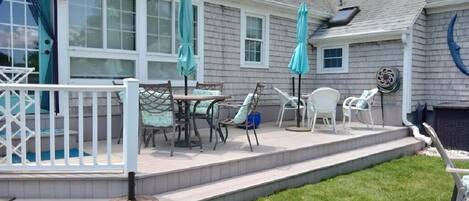 A covered patio with outdoor furniture, a white fence, and a blue door.