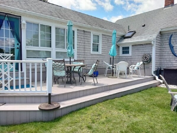 A covered patio with outdoor furniture, a white fence, and a blue door.