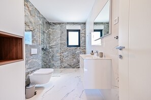 Un baño moderno con suelo de mármol, inodoro, ducha y lavamanos.