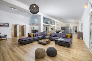 A spacious living area with a sectional sofa, round ottomans, and a modern pendant light.
