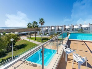 Ein Pool auf dem Dach mit klarem, blauen Wasser, umgeben von modernen Gebäuden und Palmen.