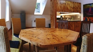 A dining area with a wooden table and wicker chairs, a kitchen in the background, and a skylight. - Villa Rotschoenberg im Tal der Freiberger Mulde (Großschirma)