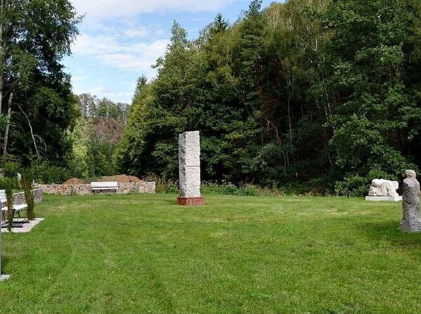 A grassy area with a stone monument and a stone statue.