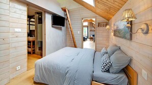 Un dormitorio con cama, televisor y techo de madera.