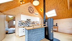 Una cabaña acogedora con cocina, chimenea de piedra y una cama.