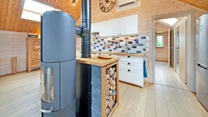 Una cocina moderna con estufa de leña, armarios blancos y salpicadero de azulejos.