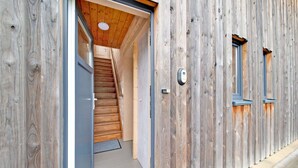Fachada de madera con una escalera que lleva a una puerta.