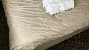 A neatly made bed with beige bedding and two rolled white towels. - Immaculate 2-bed Apartment in Bury (Bury)