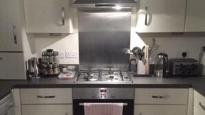 A modern kitchen with stainless steel appliances, including a stove, oven, and toaster. There are cabinets and a countertop with various kitchen items. - Immaculate 2-bed Apartment in Bury (Bury)