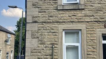 A stone building with two windows, a door, and a street lamp.