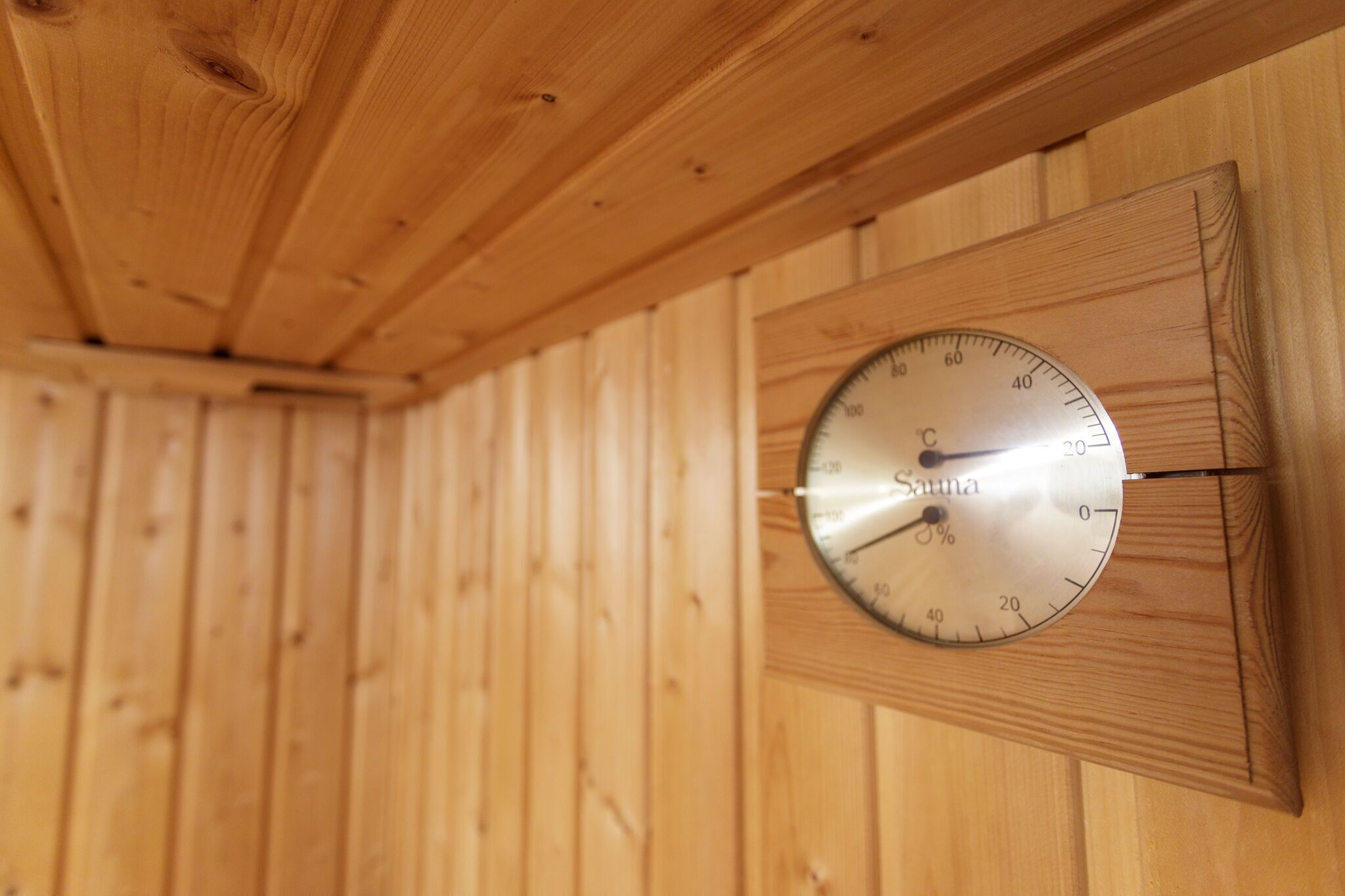 Un sauna en bois muni d’un thermomètre indiquant une température de 38 °C.