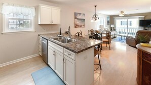 Een moderne keuken met een granieten aanrecht, witte kastjes en een ingebouwde vaatwasser.