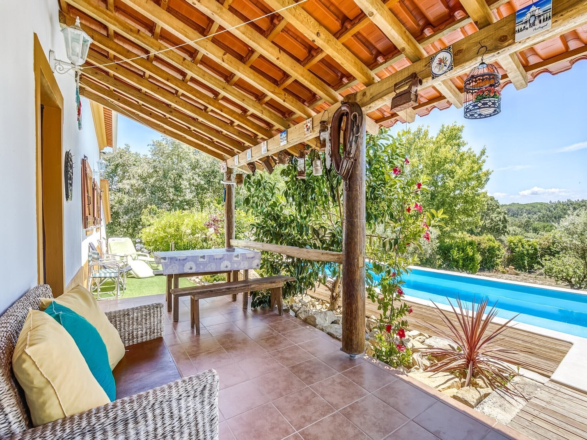 A covered outdoor seating area with a pool view, wooden beams, and decorative items.