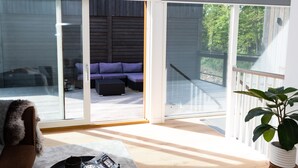 A spacious room with a large sliding glass door leading to an outdoor area with a wooden deck and a purple sofa. - Halltorp Townhouse (Borgholm)