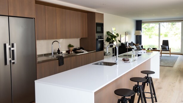 A modern kitchen with a large island, stainless steel appliances, and bar stools. - Halltorp Townhouse (Borgholm)