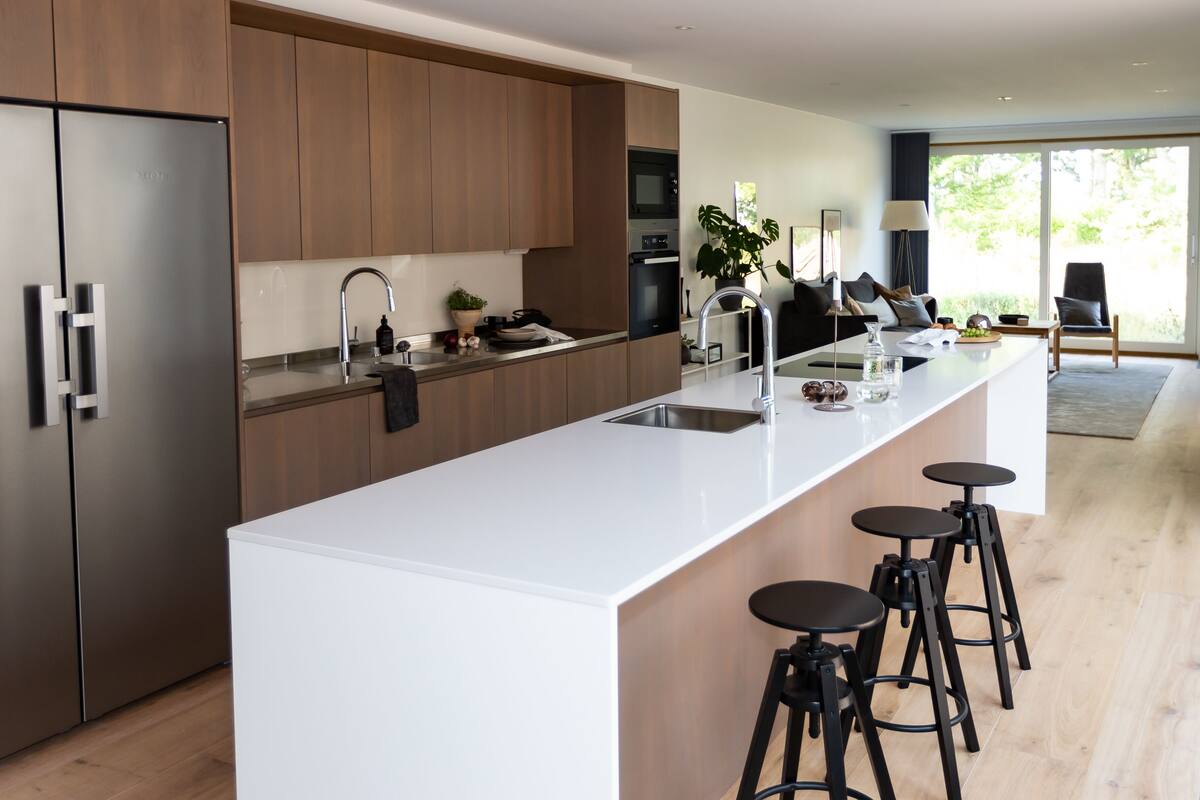 A modern kitchen with a large island, stainless steel appliances, and bar stools.