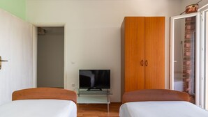 A bedroom with two single beds, a television on a glass table, and a wooden wardrobe. - Holiday Home in Rogoznica near Beach (Rogoznica)