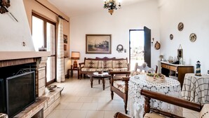 A cozy living room with a fireplace, a sofa, a table, and various decorative items. - Holiday villa with sea view in Paralia Avlidas (Tanagra)