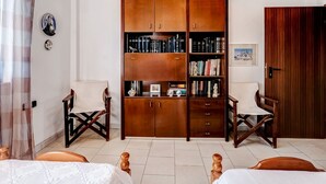 A room with a large wooden bookshelf filled with books, two wooden chairs, a bed with a white cover, and a wooden wardrobe. - Holiday villa with sea view in Paralia Avlidas (Tanagra)