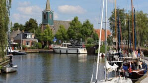 En kanal med både, en kirke og en række huse.
