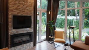 A modern living room with a fireplace, large windows, and a comfortable seating area. - Nature-Connected Modern Stay (Hoenderloo)