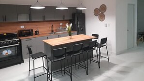 Une cuisine moderne dotée d’un îlot central, de chaises noires et de luminaires suspendus.