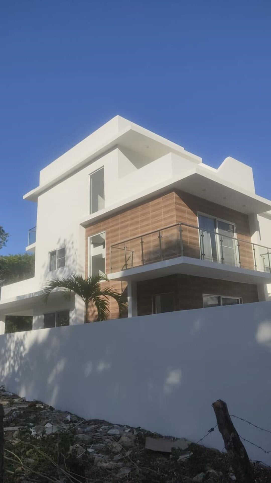 Un edificio moderno su due piani con facciata bianca, ampie finestre e un balcone con ringhiere in vetro.