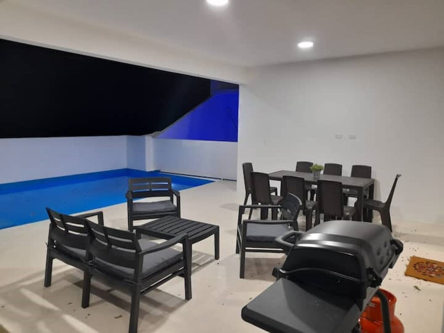 Una habitación con mesa de billar, varias sillas, un sofá y una pequeña mesa con una planta.