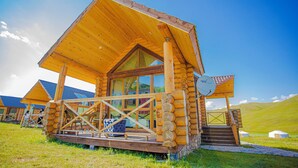A wooden log cabin with a balcony, large windows, and a satellite dish. - Bayan Mongolian Resort - Genghis Khan Statue (Erdene)