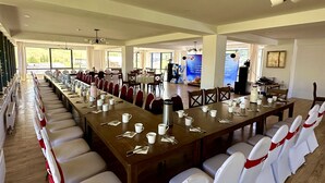 A large conference room with long tables, white chairs with red sashes, and a stage with balloons. - Bayan Mongolian Resort - Genghis Khan Statue (Erdene)