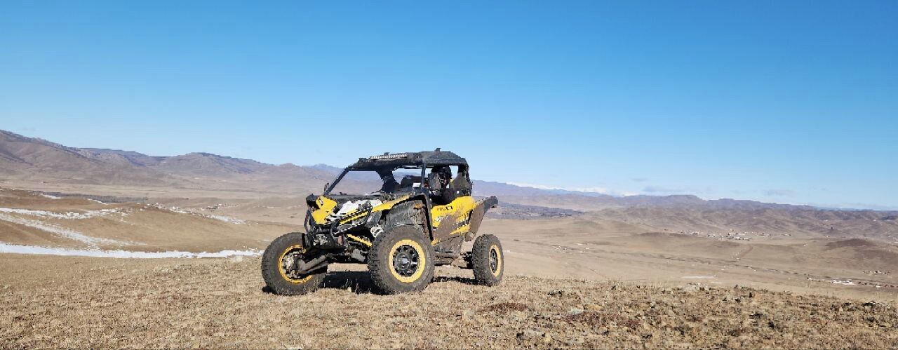 A yellow off-road vehicle in a barren landscape.