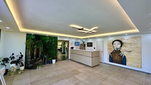 A reception area with a modern design, including a reception desk, a green wall with plants, and a large painting on the wall. - Bayan Mongolian Resort - Genghis Khan Statue (Erdene)