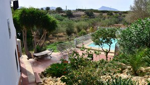A pool area with lounge chairs, a small garden with rocks and plants, and a view of a hilly landscape. - Villa with pool (Trappeto)