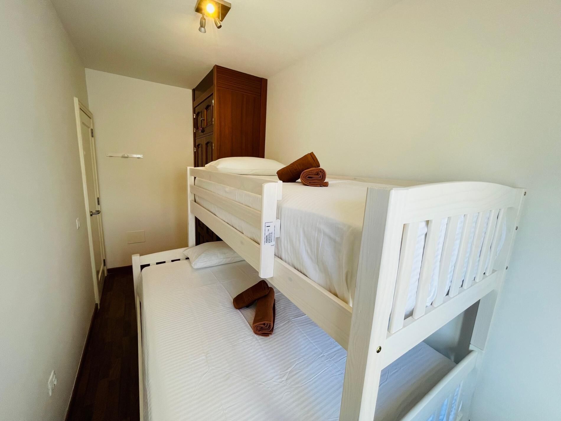 Quarto com beliche, guarda-roupa de madeira e uma porta.